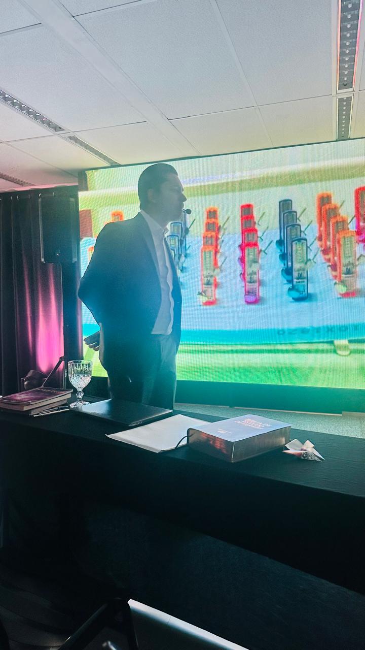 Gustavo Coelho em silhueta no palco, com uma Bíblia sobre a mesa em primeiro plano